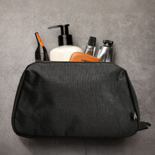 A black toiletry bag containing various personal care products, featuring a logo.