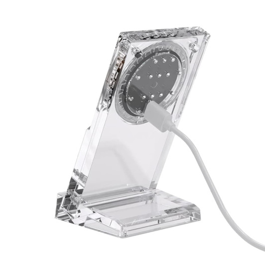 A transparent acrylic magnetic wireless charging stand with a white charging cable connected.