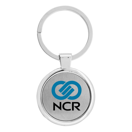 A silver keychain featuring a circular design with a branding logo on a metal surface.