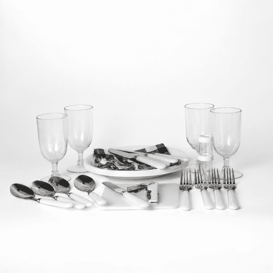 A picnic set features white-handled cutlery, glass tumblers, and serving platters on a white background.