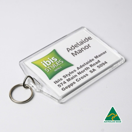 A clear hotel keychain with a ring, featuring green and white branding and a printed address. Australian made.
