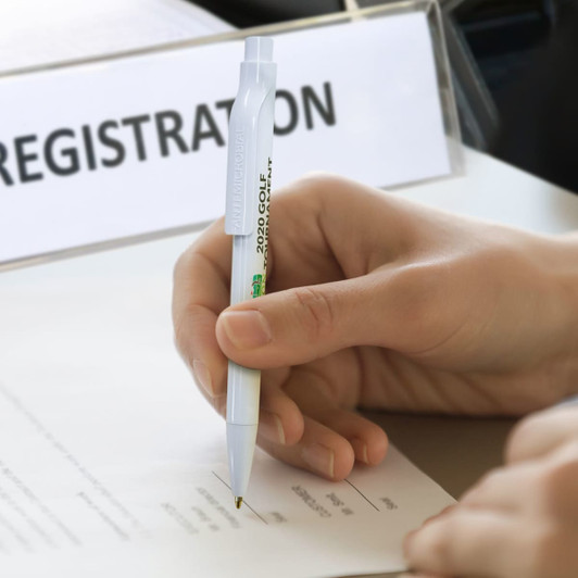An anti-microbial pen in white is held above a sheet of paper for signing or writing.