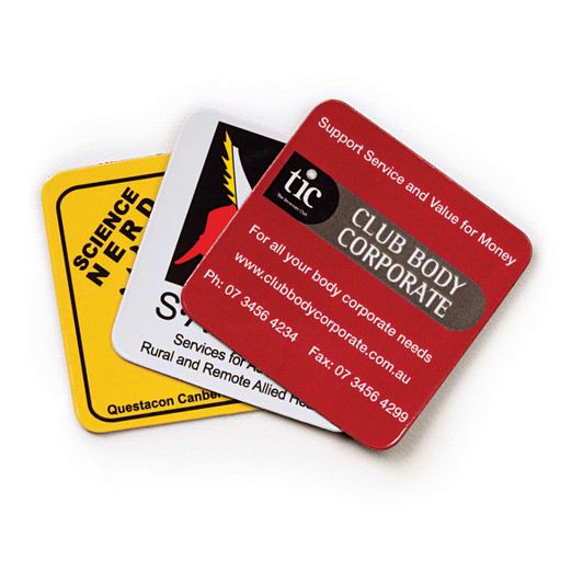 A set of three square fridge magnets in yellow, red, and grey, featuring logos and various designs.