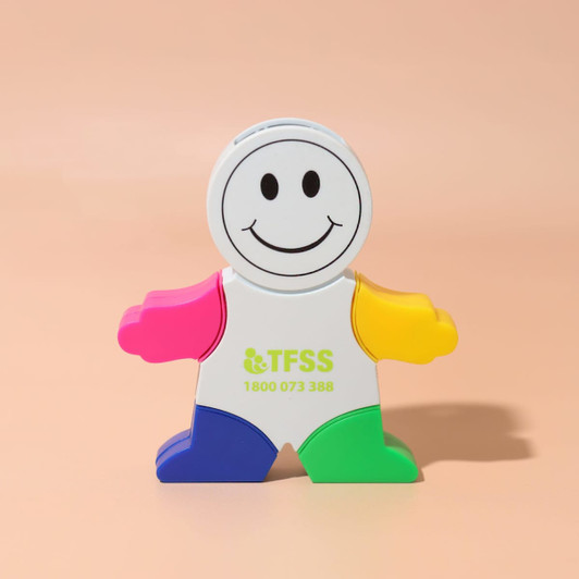 A smiling character-shaped highlighter with pink, yellow, green, and blue colours, featuring a logo on the front.