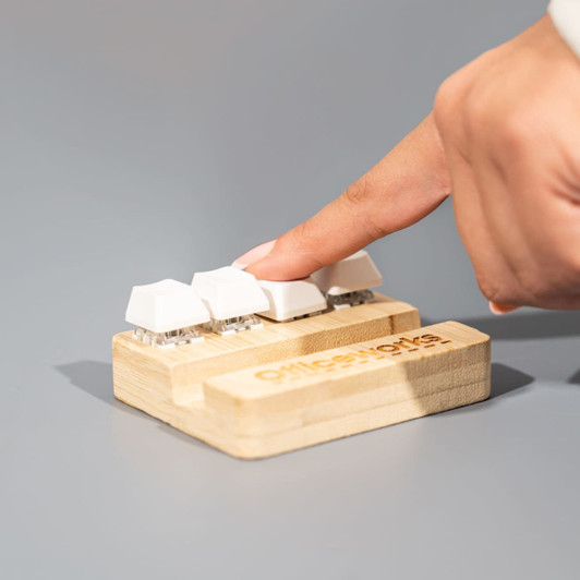 A bamboo stand holder with three white key-shaped buttons, designed for stress relief, featuring a logo.