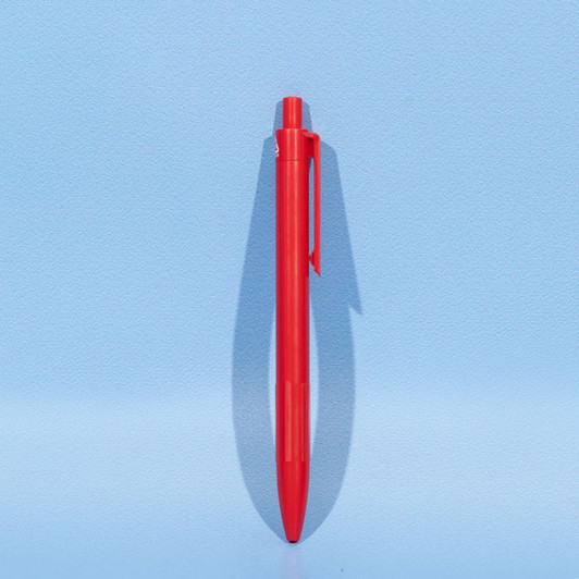 A red plastic ball pen stands upright against a light blue background, featuring a simple design and a logo.
