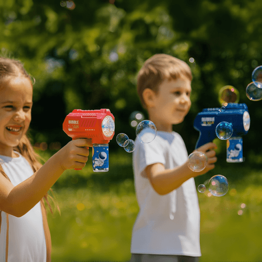 A red and a blue bubble gun are held by children, creating bubbles against a blurred green backdrop.