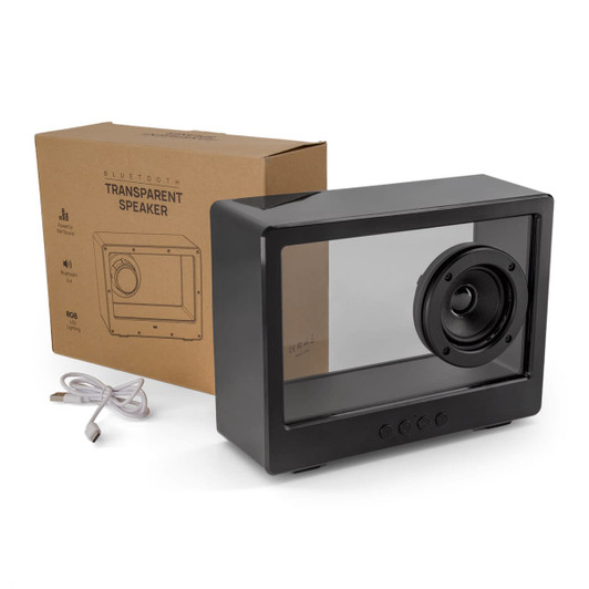 A black transparent speaker sits next to its box and a charging cable, showcasing a unique design with a visible speaker cone.