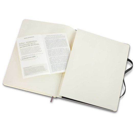 An extra large Moleskine soft cover notebook in black, open to reveal blank pages and a branded insert.