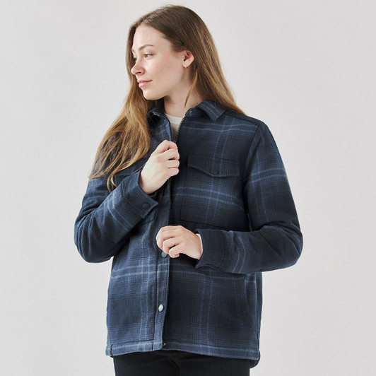 A woman wearing a navy plaid jacket with a Sherpa lining, featuring a button-up design and chest pocket.