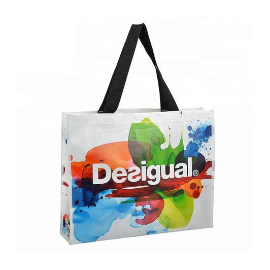 A laminated non-woven trade show bag featuring a vibrant design with splashes of colour and a black strap.
