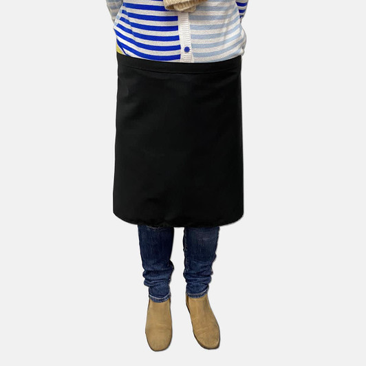A black waist apron worn by a person, paired with blue jeans and beige boots, with a striped top above.
