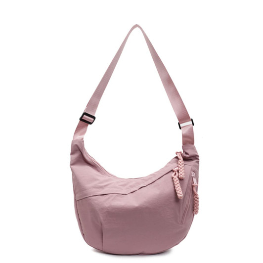 A pink crossbody bag with a curved shape, featuring a braided zipper detail and an adjustable strap.