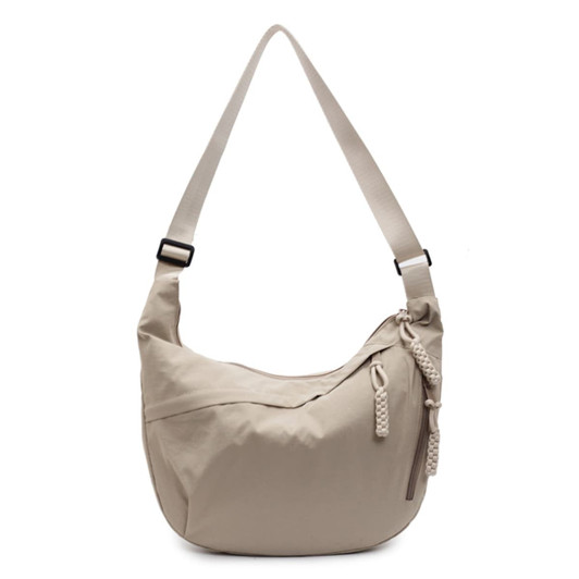 A beige crossbody bag with a woven zipper pull and an adjustable strap. It has a brand logo visible on the side.