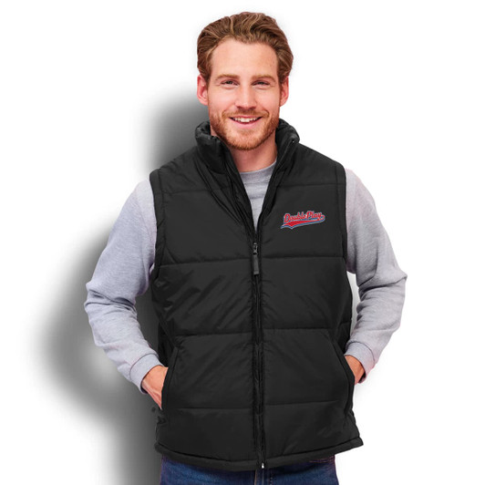 A man wearing a black padded unisex vest, featuring a logo on the chest, and a grey long-sleeve shirt underneath.