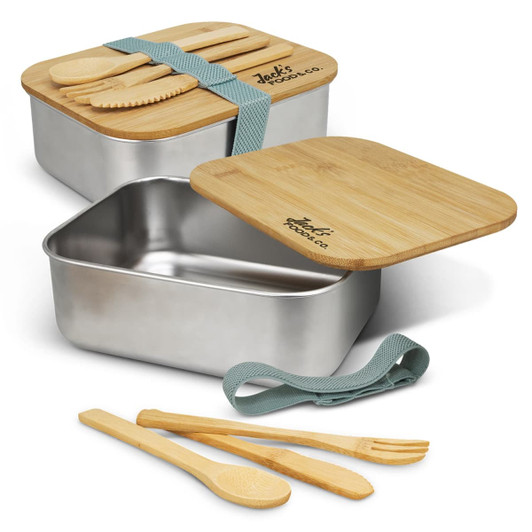 A stainless steel lunch box with a bamboo lid and cutlery, featuring a green strap. Contains wooden spoons and fork.