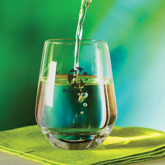 A stemless glass filled with liquid, featuring a reflective surface and a colorful background.