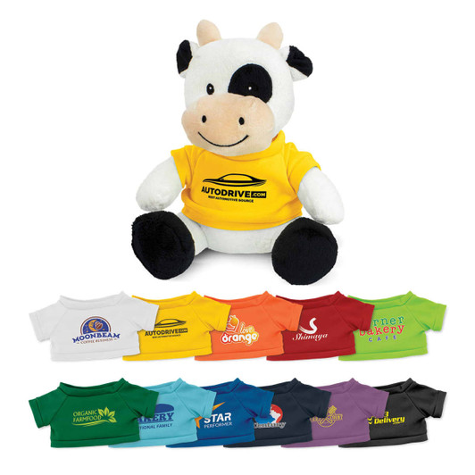 A cow plush toy with a black and white colour scheme, wearing a yellow shirt featuring a logo. Various other shirts are displayed below.
