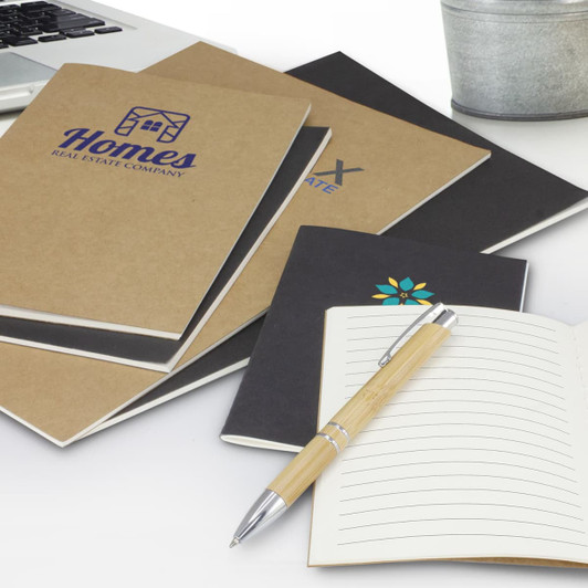 A collection of notebooks in brown and black, featuring various designs and a pen on a desk with a plant.