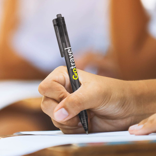 A black plastic pen with a logo, being held while writing on paper.
