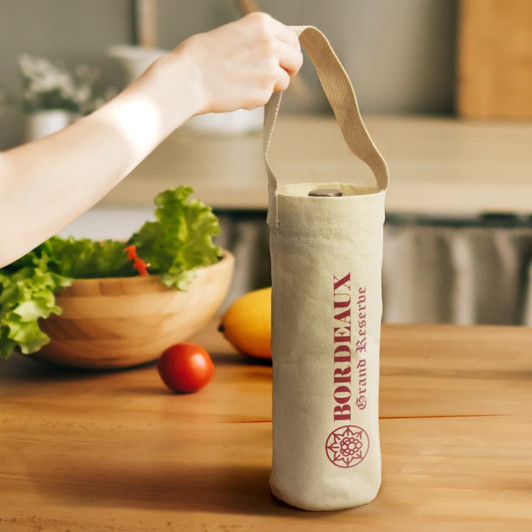 A cotton wine tote bag in natural colour with a logo, held by a hand. There are vegetables and fruits in the background.