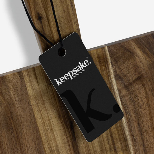 A wooden chopping board with a dark brown finish and a black branded tag attached.