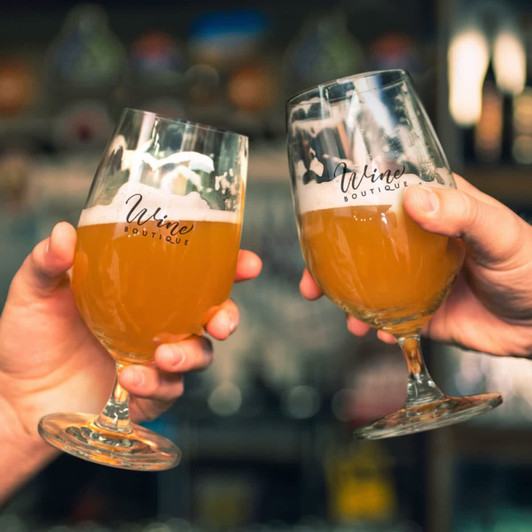 Two elegant beer glasses filled with amber beer, featuring a logo, held up as a toast.