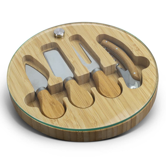 A bamboo cheese board with a glass top, featuring four stainless steel cheese knives fitted in circular compartments.