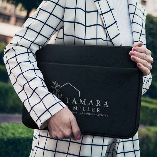 A large black laptop sleeve with a logo, being held by a person in a white and black checkered blazer.