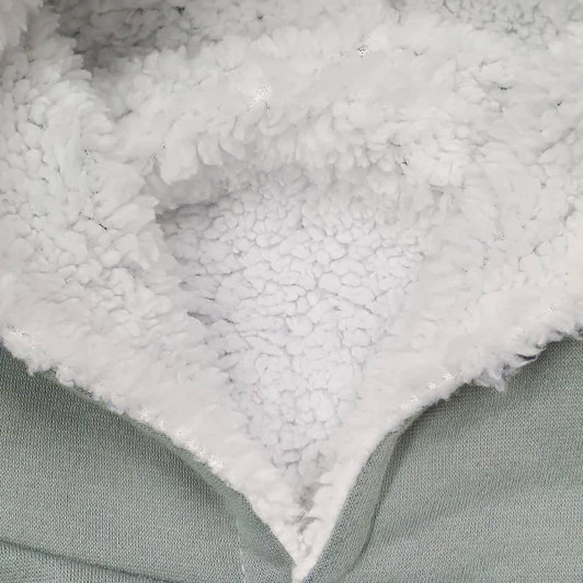 A detail of a soft, fluffy inner lining in a hoodie, featuring grey outer material and textured white fleece.
