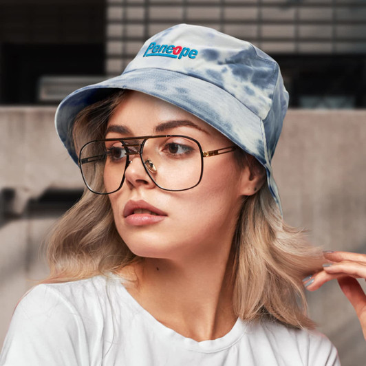A blue tie-dye bucket hat with a logo on the front, worn by a person with glasses and long hair.