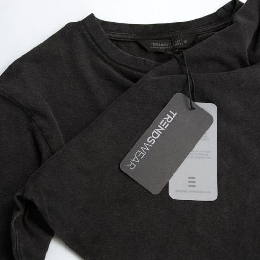 A faded black unisex T-shirt featuring a logo and a hang tag detailing care instructions.