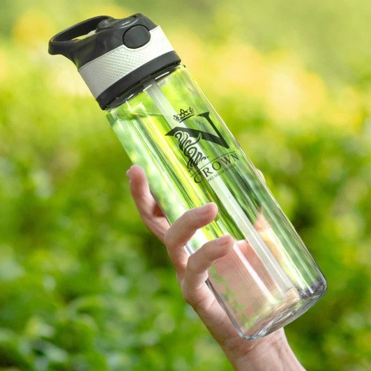 A drink bottle in clear plastic with a black top and silver band, featuring a logo and held against a green background.