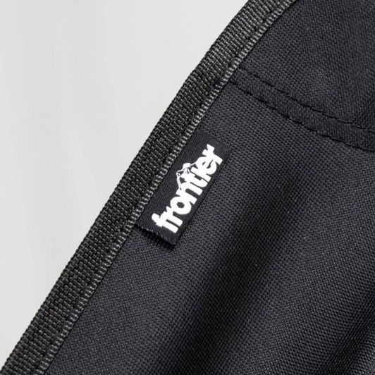 A black fabric showing stitching and a logo tag for a folding chair.