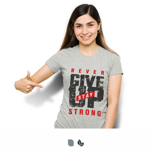 A woman wearing a grey T-shirt with motivational text and a logo, pointing towards the shirt.