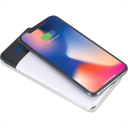 A wireless power bank in white with a display, featuring a smartphone on top showing a charging indicator.