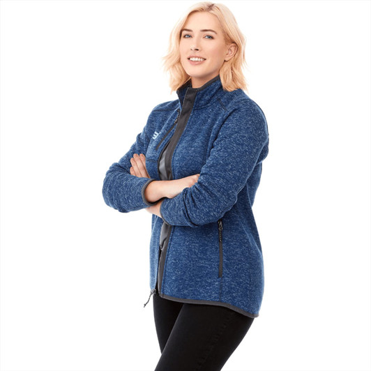 A women's knit jacket in a blue and black colour scheme, featuring a zipper and side pockets. It has a logo on it.