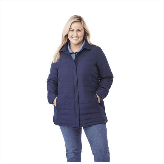 A woman wearing a navy insulated shacket with a button-up front and two pockets. It has a branding logo.