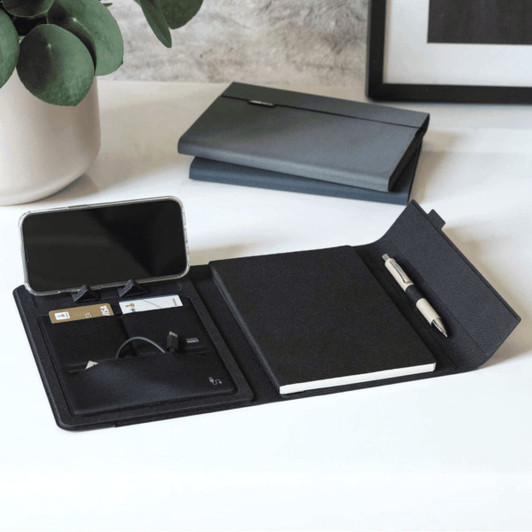 A5 RPET folio notebook in black, featuring a notepad, pen, card holder, and phone slot, with a grey folder in the background.