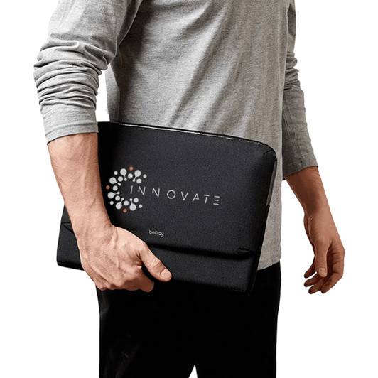 A black laptop caddy being held by a person, featuring a logo on the front.