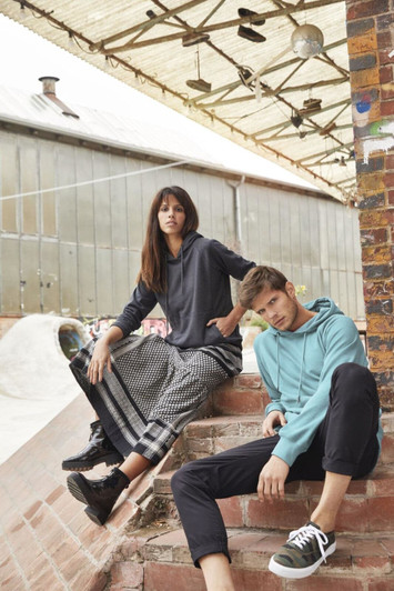 A hooded jumper in teal and a hooded jumper in dark grey are worn by two models sitting on steps.