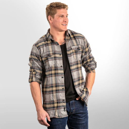 A man in a grey and yellow plaid flannel snap shirt, wearing a black t-shirt underneath and blue jeans.