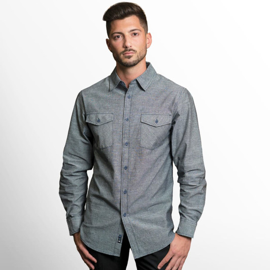 A long sleeve chambray shirt in grey with button-up front and chest pockets, featuring a logo.