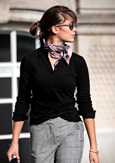 A black women's polo shirt styled with a scarf, worn by a woman outdoors.