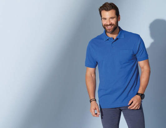 A blue polo shirt with a pocket, modelled by a smiling man, against a soft blue background.