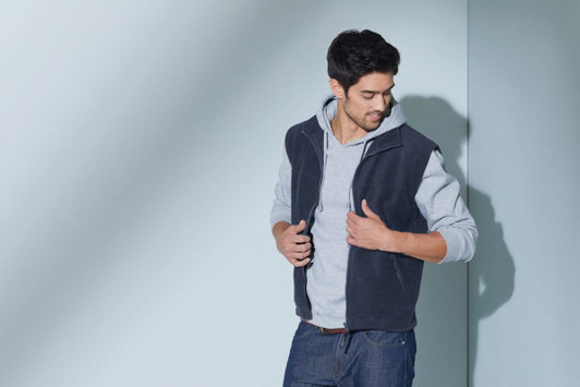 A fleece vest in navy blue, worn over a light grey hoodie, featuring a zip front and pockets.