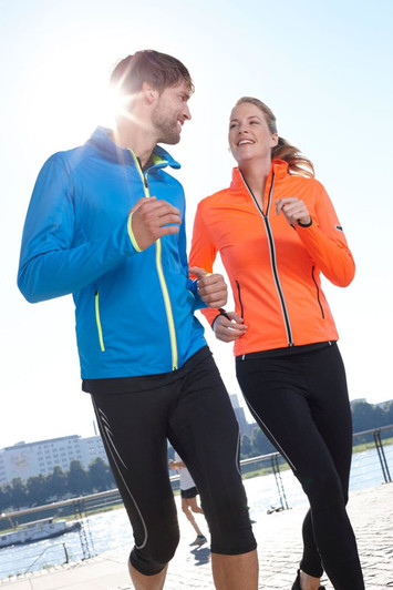 A blue men's softshell jacket and an orange women's softshell jacket, both with zippers, worn by two runners outdoors.