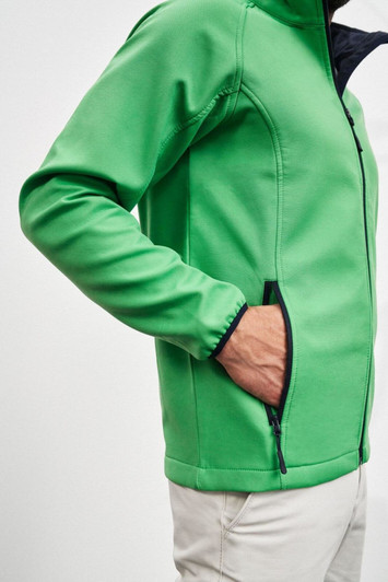 A green softshell jacket with a zipper and pockets, featuring a black interior and sleeve detailing.