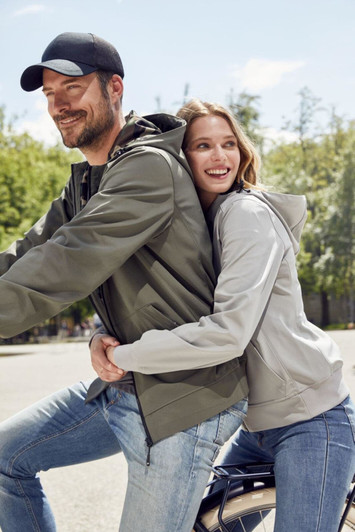 A grey ladies hooded softshell jacket worn by a woman with a man in a green jacket, both smiling outdoors.