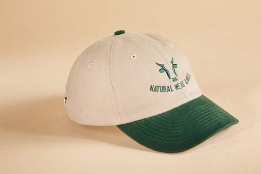 A beige cap with a green peak and a logo on the front, featuring a six-panel design.